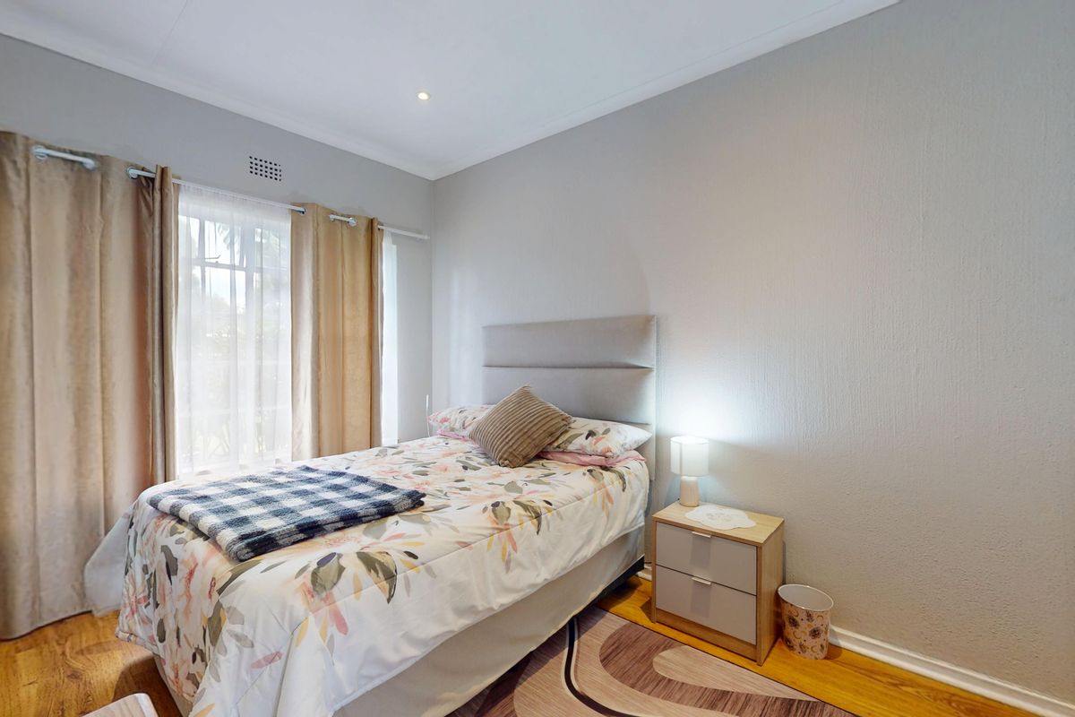 A well-maintained bedroom featuring hardwood flooring, neutral wall finishes, and recessed lighting, offering a comfortable and functional living space.