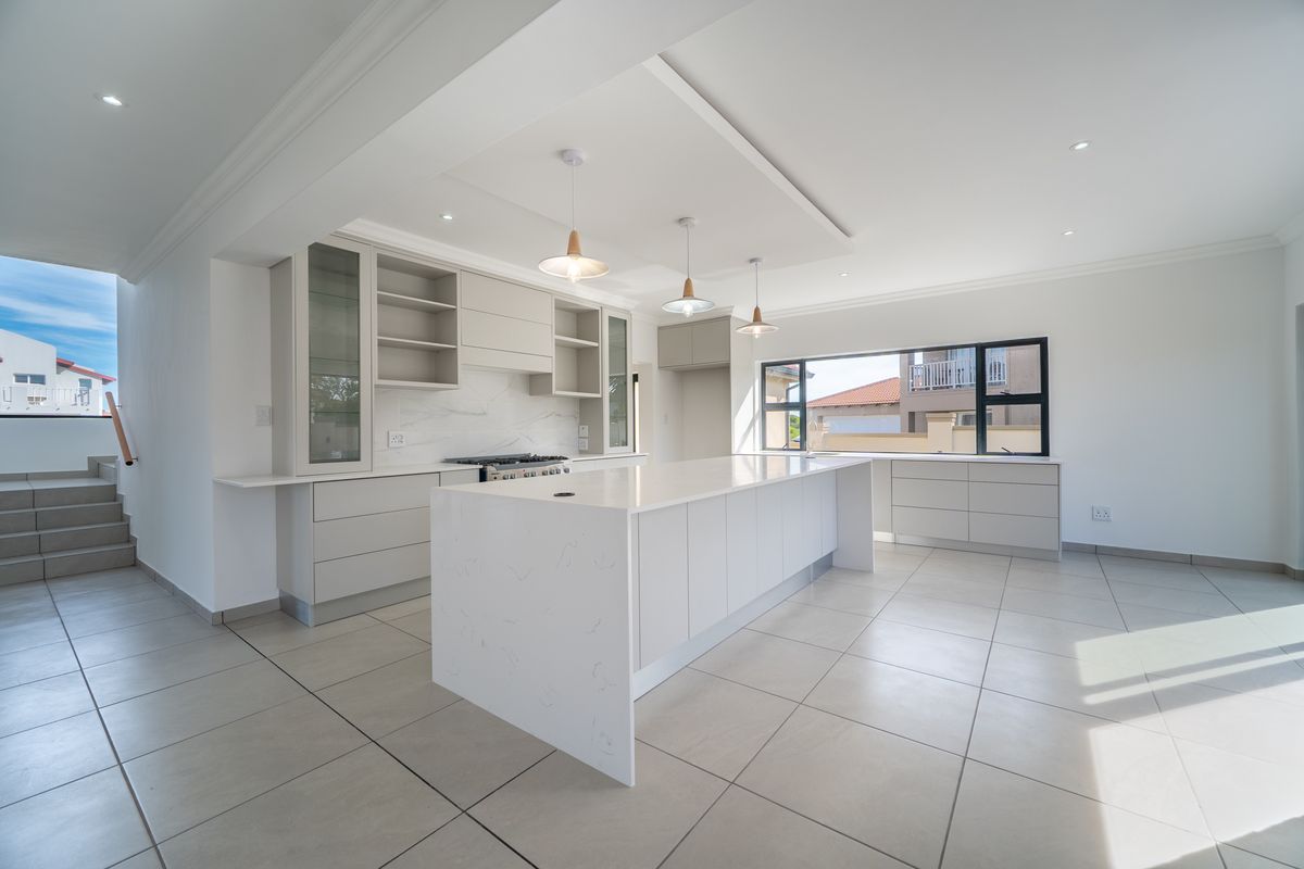 Modern, spacious kitchen featuring a large central island with quartz countertops, sleek built-in cabinetry, and high-quality tiled flooring in an open-plan layout.