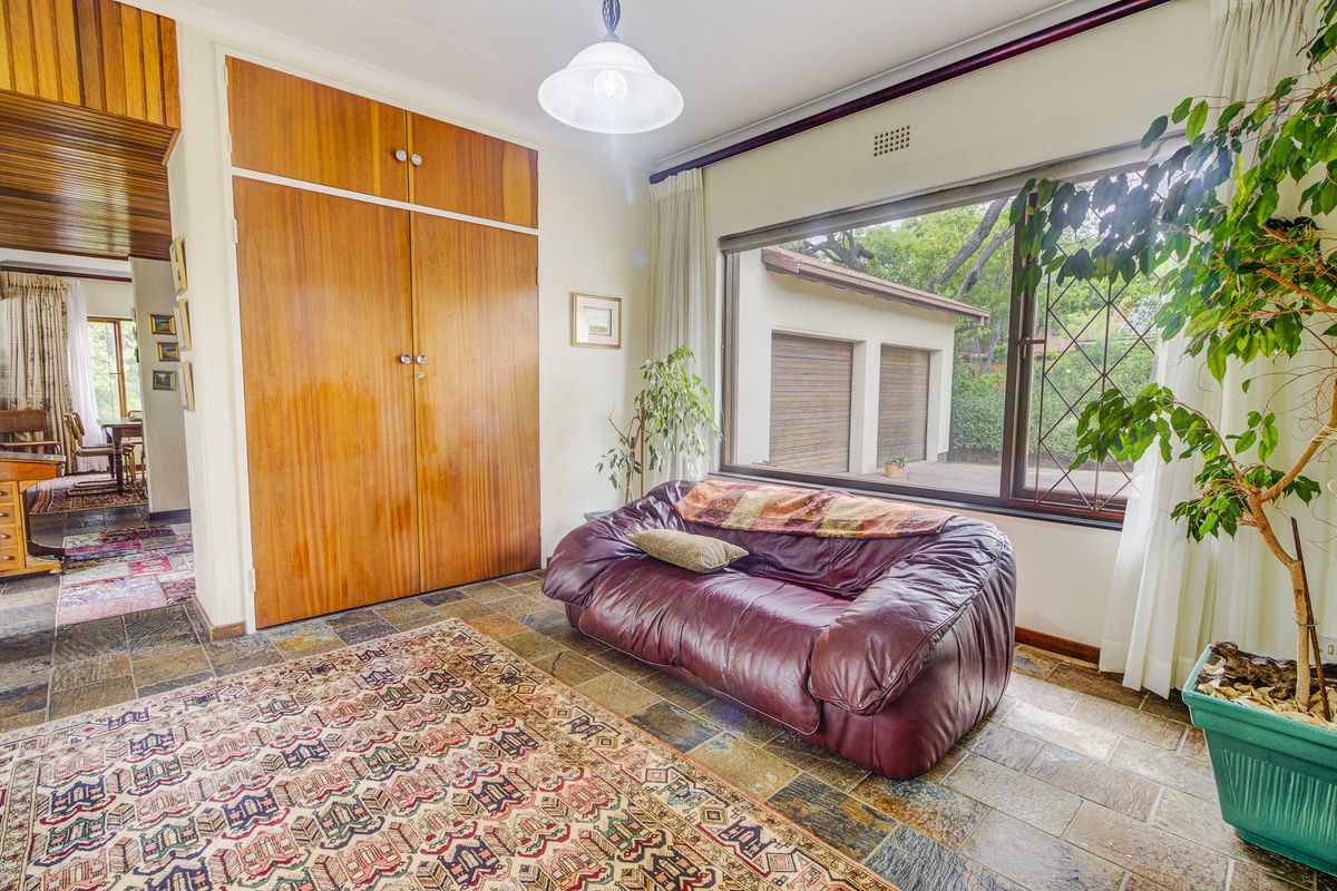 A living area featuring durable slate tile flooring, built-in wooden cabinetry, and a large window providing natural light and views of the exterior.