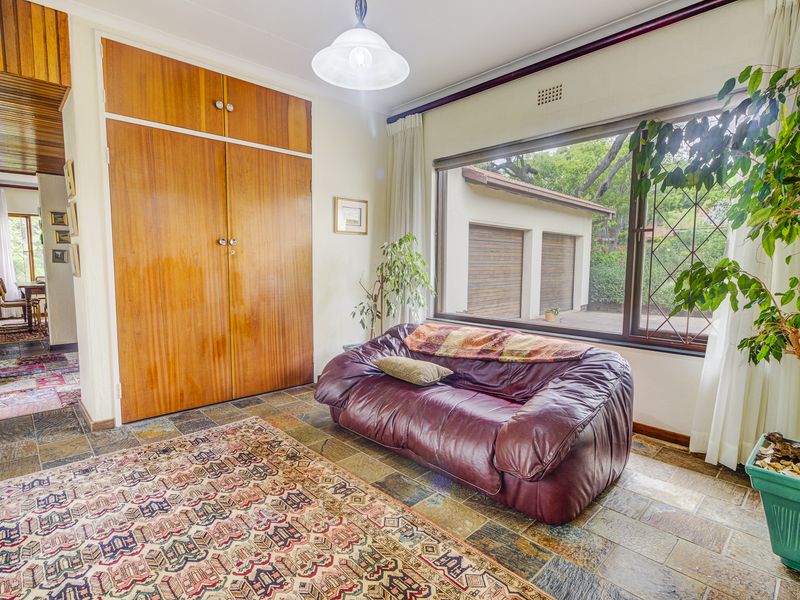 A living area featuring durable slate tile flooring, built-in wooden cabinetry, and a large window providing natural light and views of the exterior.