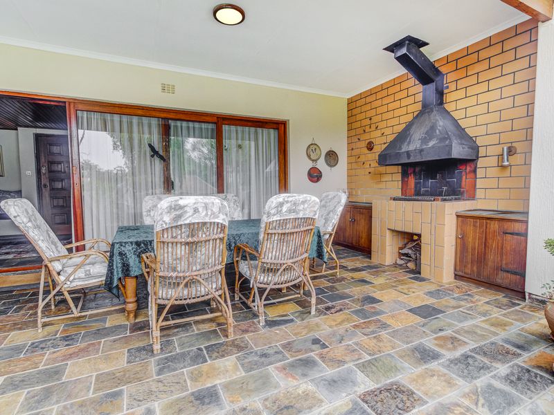 Covered patio area featuring a built-in brick braai, slate tile flooring, and direct access to the interior through large sliding glass doors.