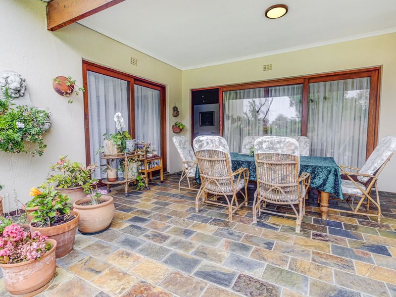 A covered patio area featuring durable slate tile flooring and large sliding glass doors that provide seamless access to the interior living spaces.