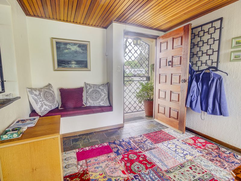 Welcoming entrance hall featuring a solid timber door, slate flooring, and a built-in bench with a warm timber-paneled ceiling.