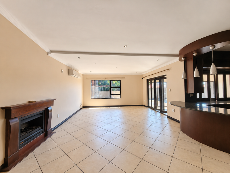 Spacious open-plan living area featuring tiled floors, a built-in fireplace, air conditioning, and a breakfast bar, with direct access to the outdoor area.