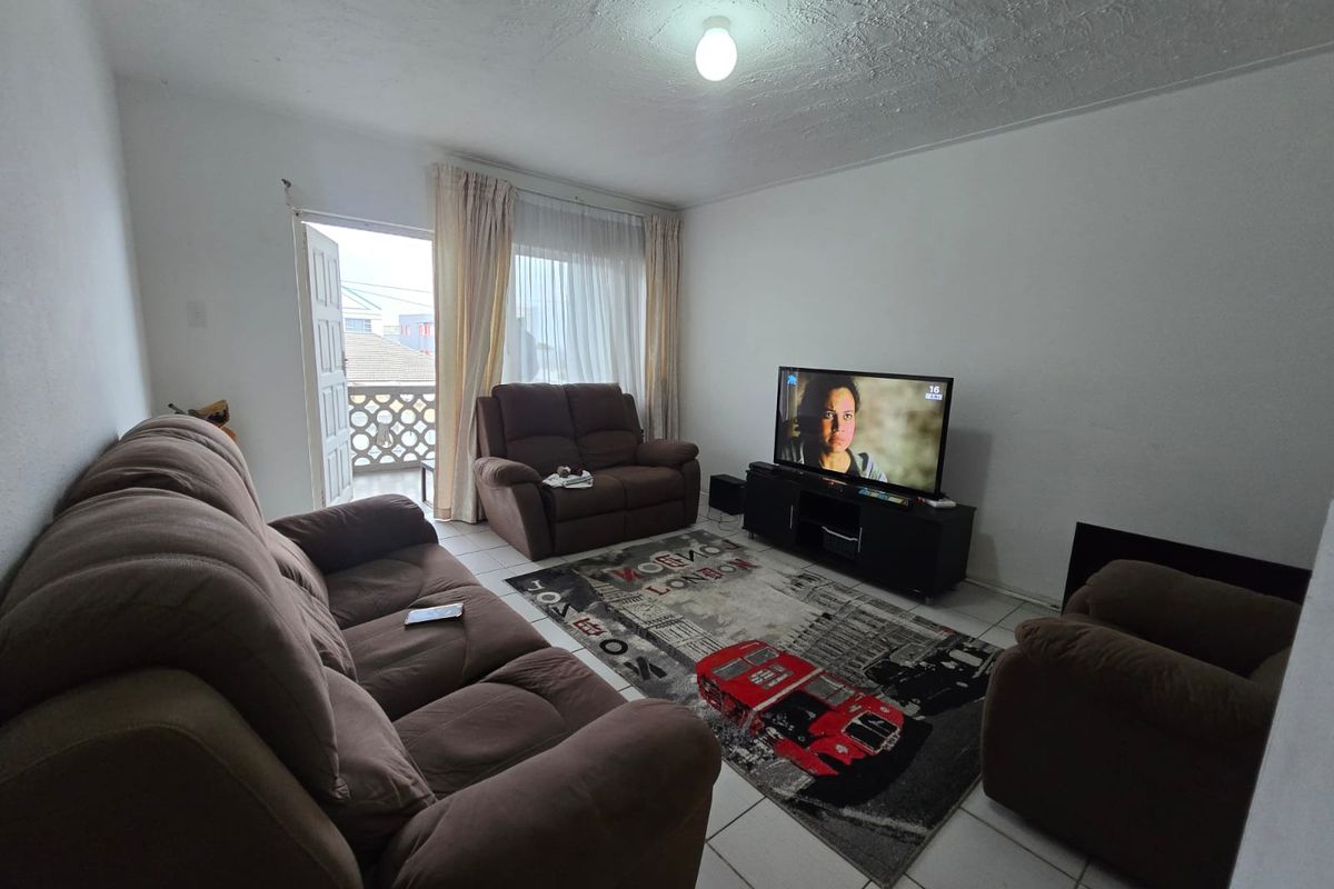 A living room featuring tiled flooring and direct access to a balcony, providing a functional space with potential for cosmetic updates.