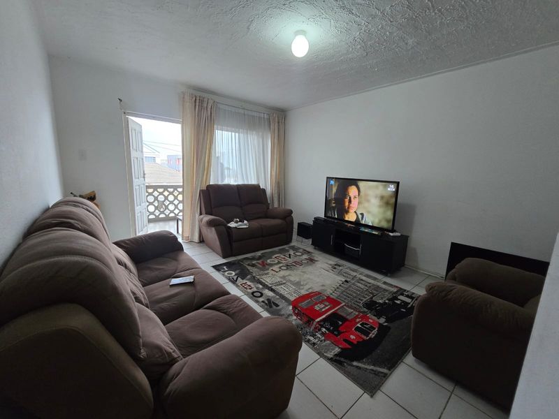 A living room featuring tiled flooring and direct access to a balcony, providing a functional space with potential for cosmetic updates.