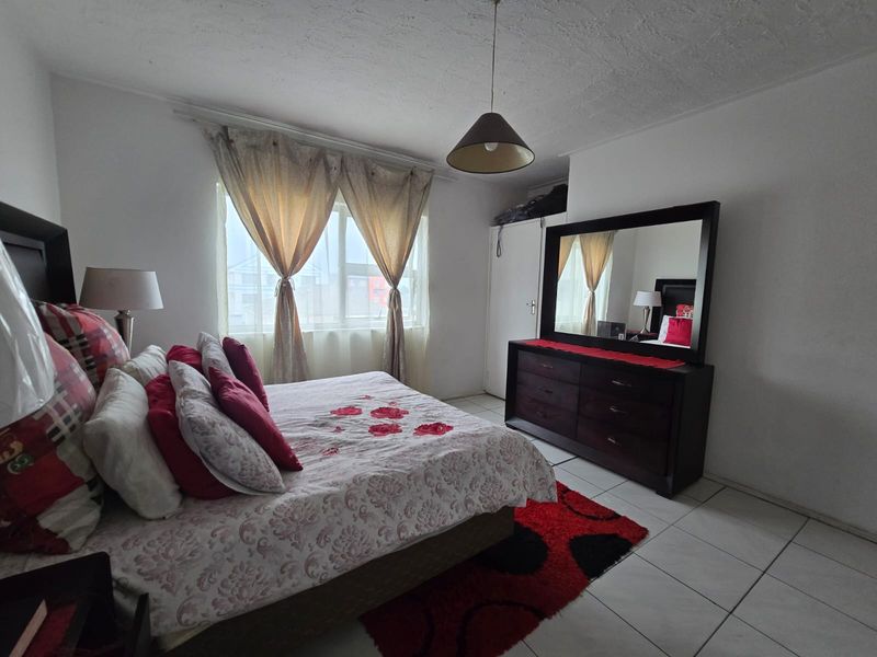 A bedroom featuring tiled flooring, a built-in wardrobe, and a window with natural light.