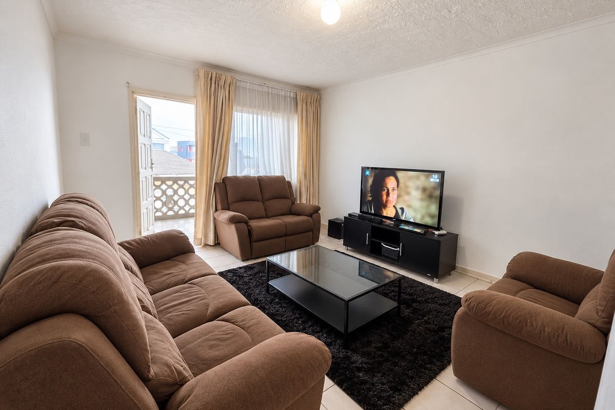 A functional living room featuring tiled flooring, textured ceilings, and direct access to an outdoor balcony area.