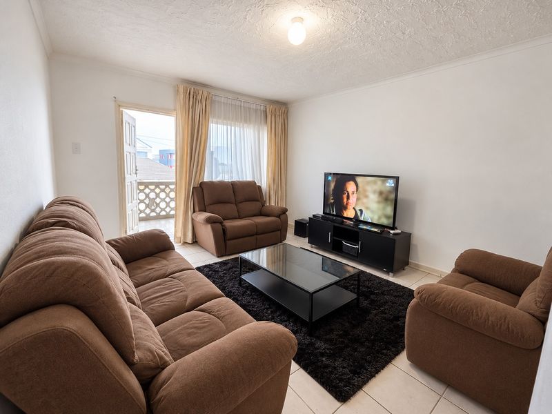 A functional living room featuring tiled flooring, textured ceilings, and direct access to an outdoor balcony area.
