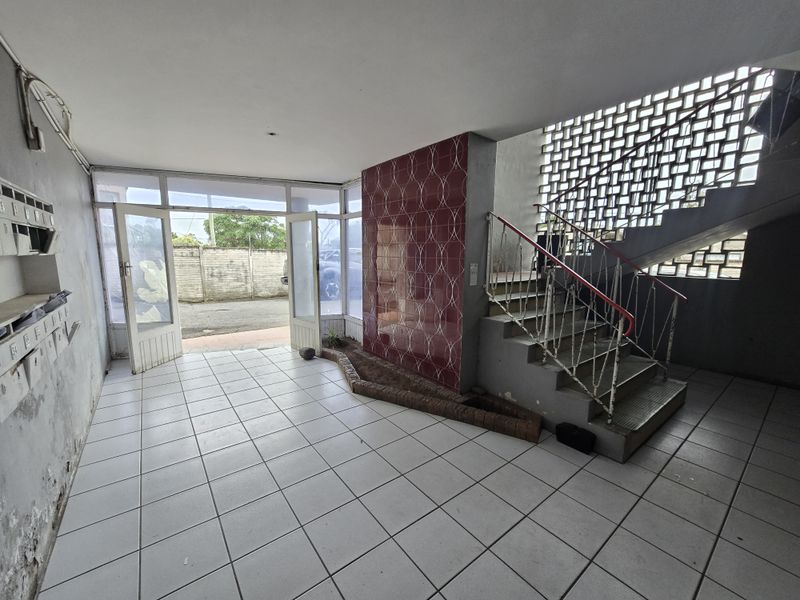 Entrance foyer featuring a decorative tiled feature wall, staircase with metal handrail, and integrated mailboxes, providing access to the apartment building.