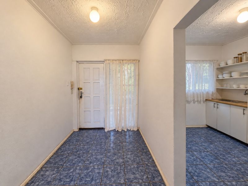 An entry area leading into a kitchen space featuring blue tiled flooring, built-in cabinetry with wooden countertops, and open shelving.