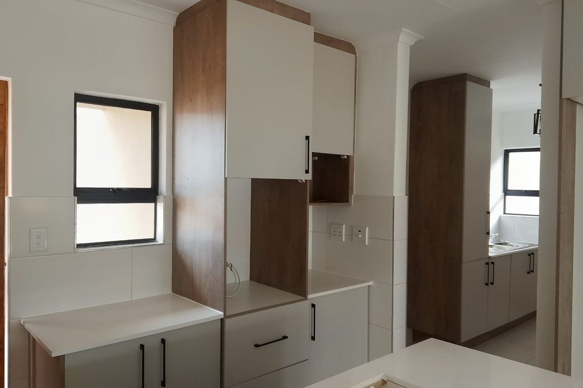 Modern kitchen featuring two-tone cabinetry, stone countertops, and tiled splashbacks, offering a clean and functional layout with ample storage space.