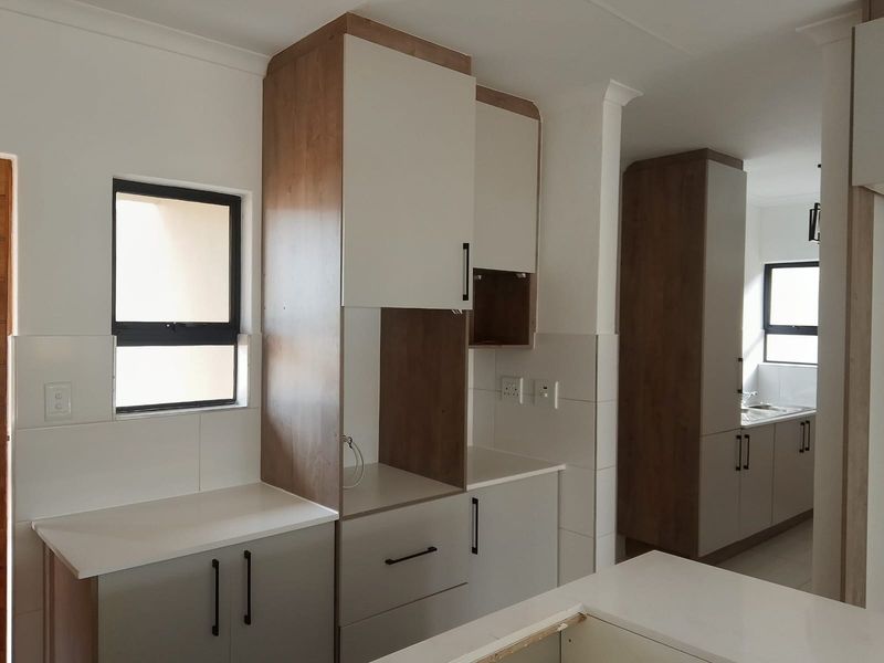 Modern kitchen featuring two-tone cabinetry, stone countertops, and tiled splashbacks, offering a clean and functional layout with ample storage space.