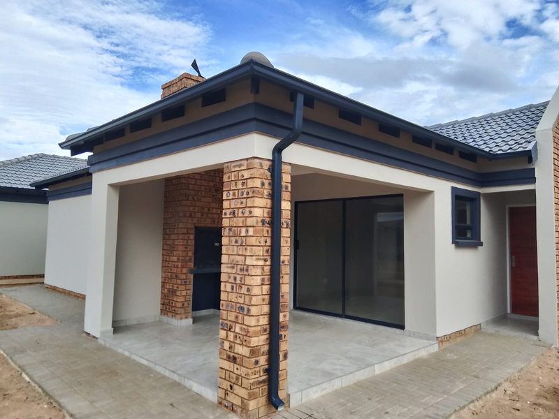 A modern covered patio featuring a built-in braai, tiled flooring, and sliding glass doors providing seamless access to the interior living space.