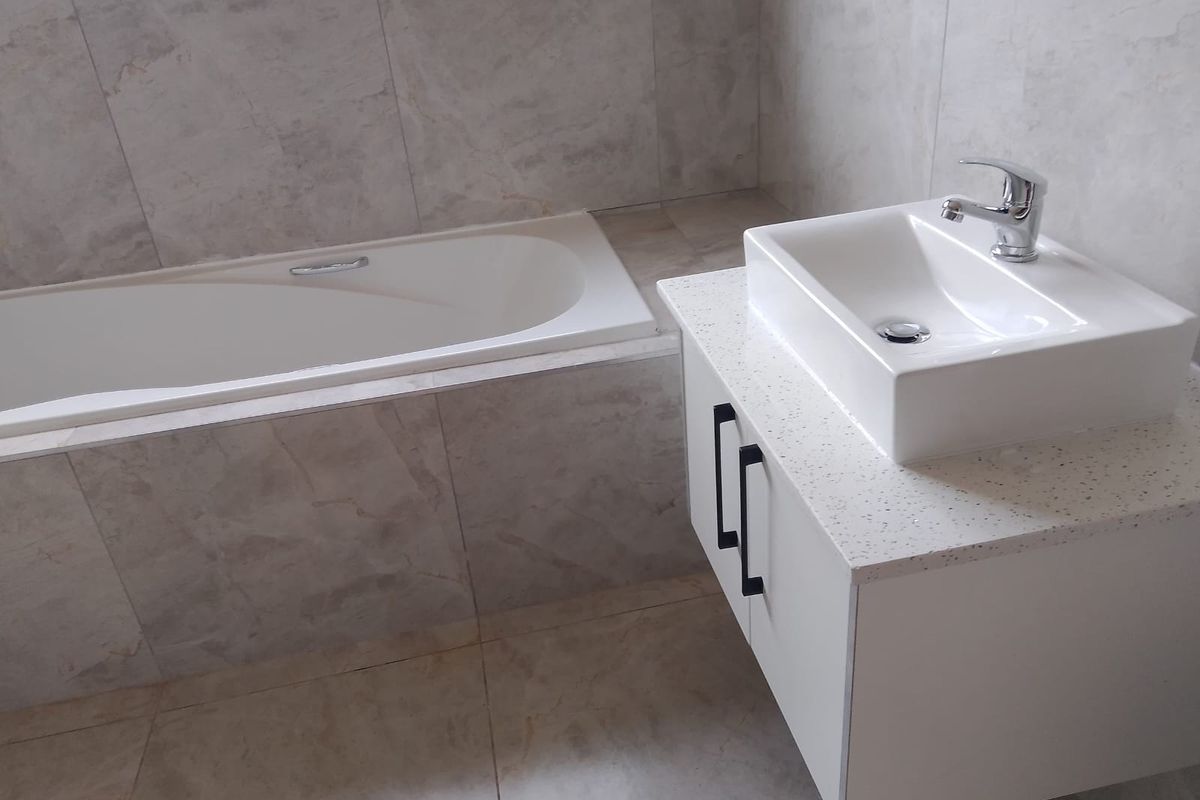 Modern bathroom featuring a built-in bathtub and a sleek wall-mounted vanity with a countertop basin and contemporary chrome fixtures.