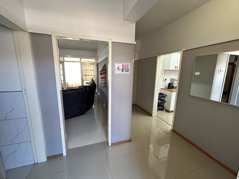 A bright hallway with tiled flooring providing access to the living area and kitchen.
