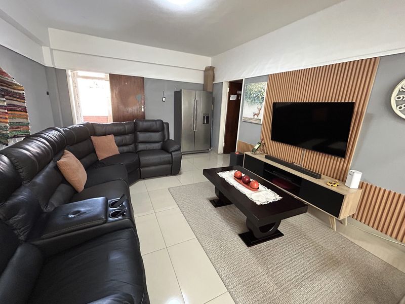 A living room featuring tiled flooring and a decorative slatted timber feature wall with integrated television mounting.