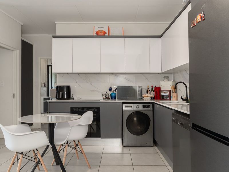 Modern kitchen featuring sleek white and grey cabinetry, marble-look splashback, integrated oven, and tiled flooring in a clean, contemporary layout.