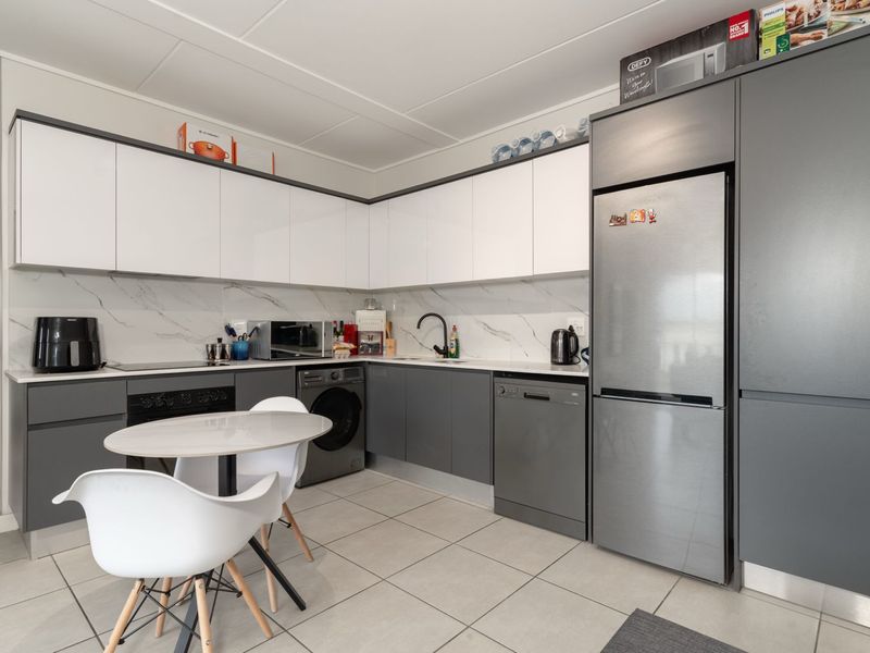 Modern kitchen featuring sleek two-tone cabinetry, marble-look backsplash, tiled flooring, and integrated appliances including an oven, hob, and dishwasher.
