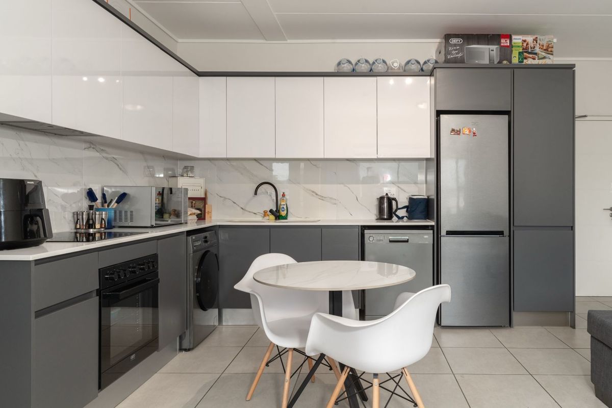 Modern kitchen featuring high-gloss cabinetry, marble-look splashback, integrated oven, and hob, with a clean, contemporary aesthetic and functional layout.