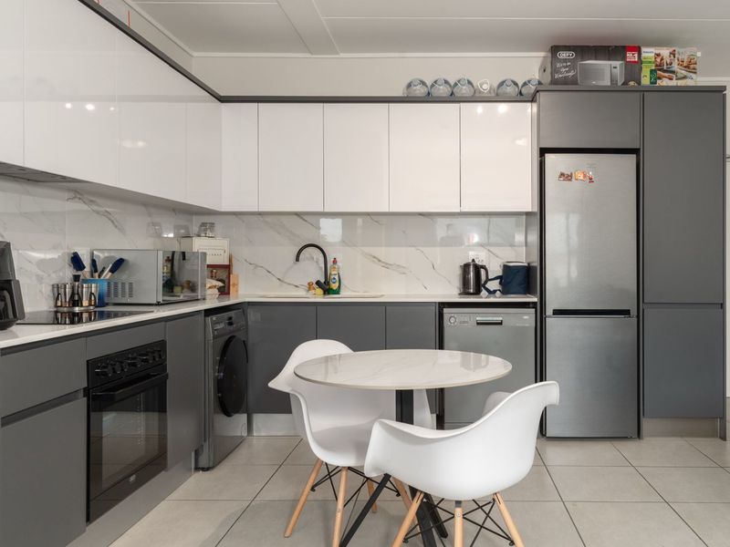 Modern kitchen featuring high-gloss cabinetry, marble-look splashback, integrated oven, and hob, with a clean, contemporary aesthetic and functional layout.