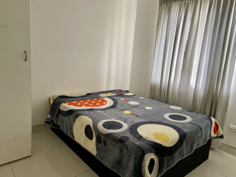 A functional bedroom featuring tiled flooring, a built-in wardrobe, and window curtains, providing a clean and neutral space.