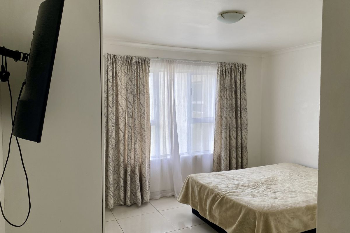 A simple bedroom featuring tiled flooring, a central ceiling light, and a window with curtains.