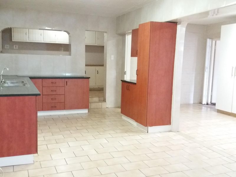Spacious kitchen featuring built-in cabinetry, laminate countertops, and tiled finishes throughout, offering a functional layout ready for modern updates.