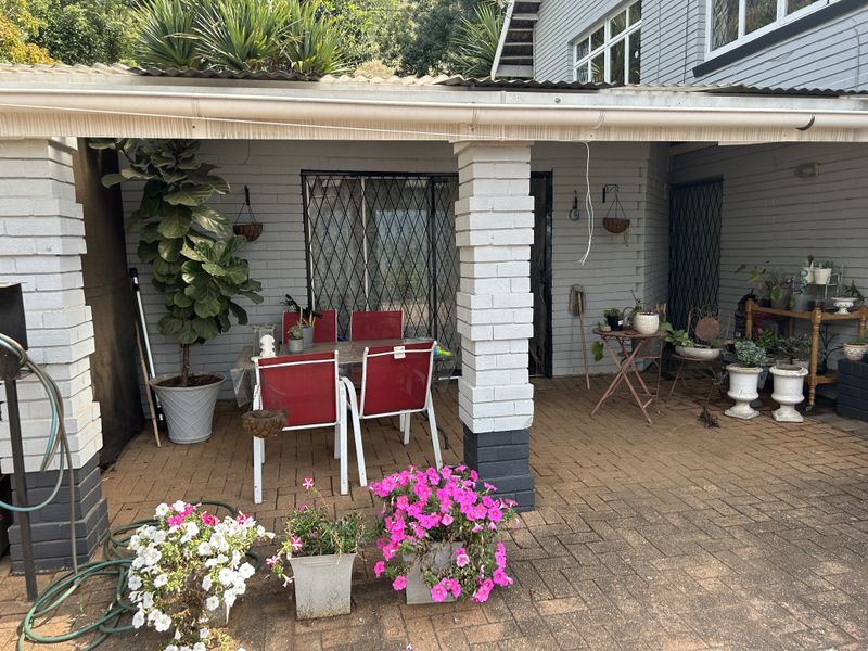 A covered outdoor patio area featuring brick paving, painted brick support columns, and direct access to the home via security gates.