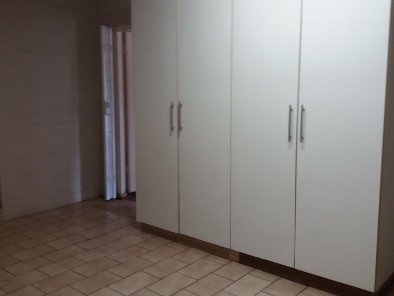 A bedroom featuring built-in cupboards and tiled flooring, offering a clean and functional space ready for personalization.