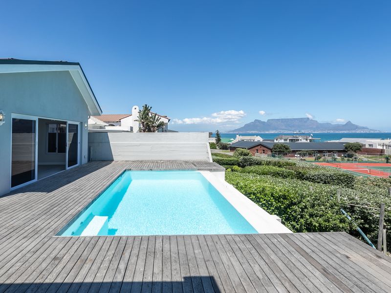 Outdoor pool area featuring timber decking, a swimming pool, and direct access to the home via sliding glass doors with scenic coastal views.