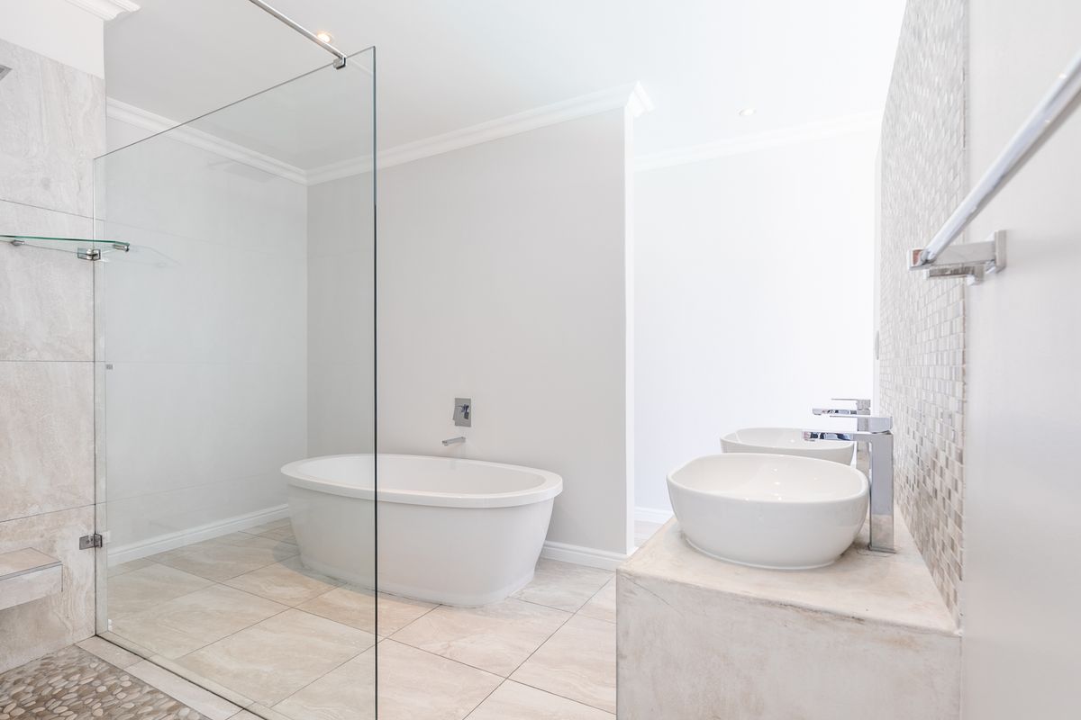 Modern bathroom featuring a freestanding bathtub, glass-enclosed walk-in shower with rain head, and a dual-sink vanity with stone countertop.