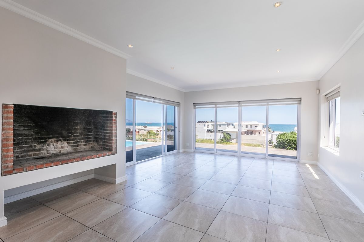 Spacious, light-filled living area featuring large sliding glass doors with ocean views, tiled flooring, and a built-in brick fireplace.