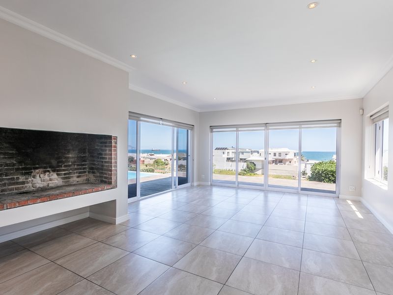 Spacious, light-filled living area featuring large sliding glass doors with ocean views, tiled flooring, and a built-in brick fireplace.