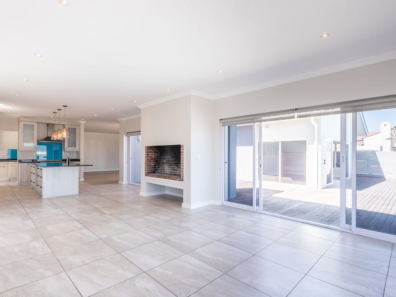 Spacious open-plan living and kitchen area featuring tiled floors, a built-in fireplace, and large sliding doors opening to an outdoor deck.