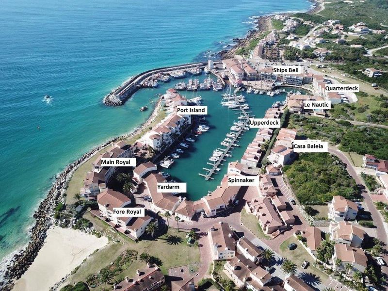 Aerial view of a coastal residential marina development featuring multiple apartment blocks, private boat moorings, and direct access to the ocean.