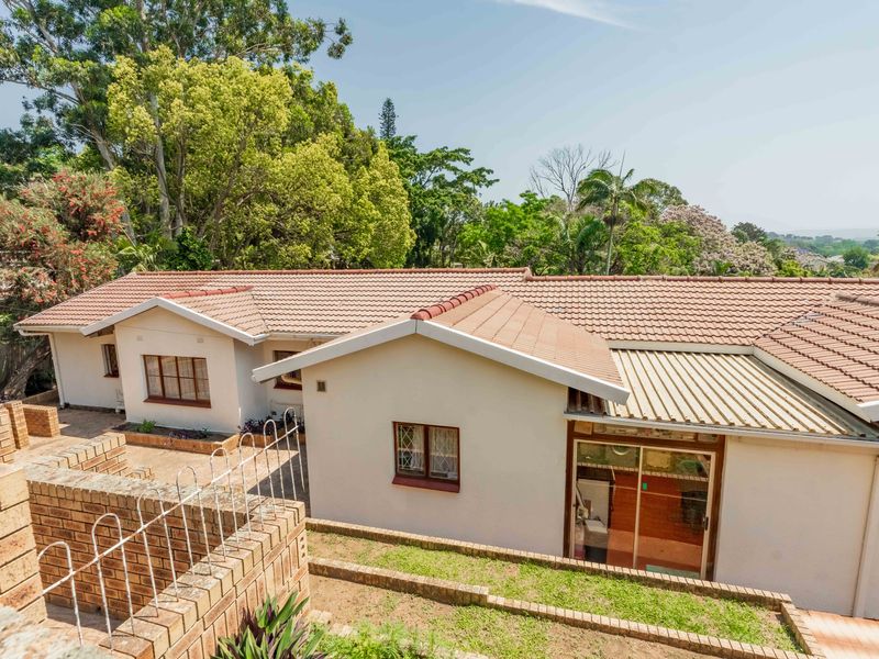 Rear view of the house featuring a terracotta tiled roof, brick retaining walls, and a sliding glass door leading to the interior.