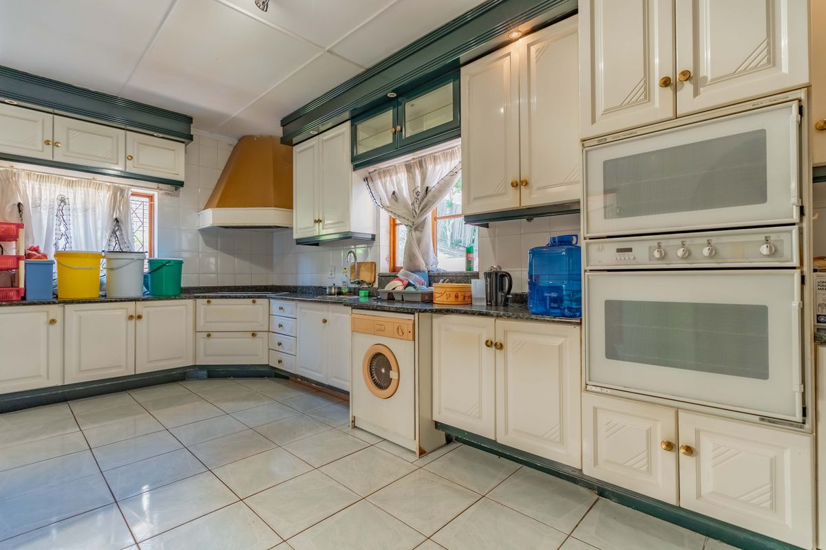 A spacious kitchen featuring traditional white cabinetry, granite countertops, a double wall oven, and tiled flooring, offering a functional layout with ample storage space.