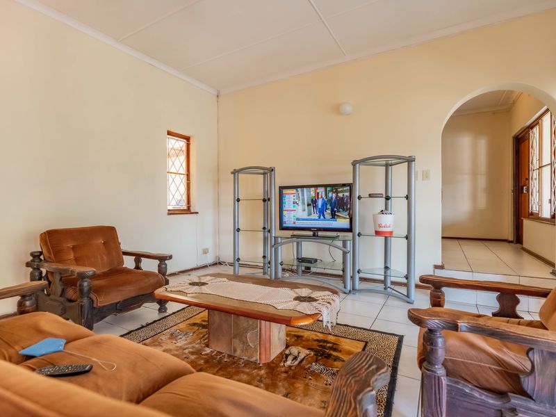 A living room featuring tiled flooring, an arched entryway, and a leaded glass window, providing a functional and traditional living space.