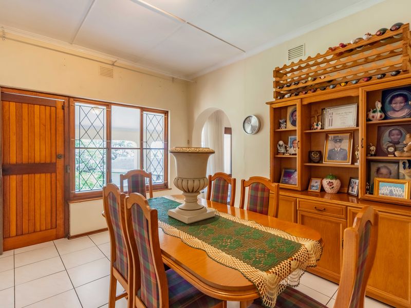 Dining room featuring tiled flooring, leaded glass windows, a timber door, and extensive built-in timber cabinetry with an integrated wine rack.