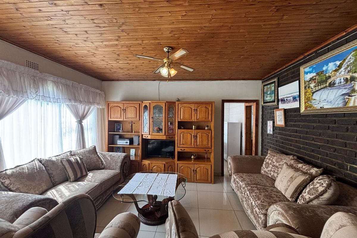 A living room featuring a warm timber ceiling, exposed brick feature wall, and tiled flooring, offering a cozy and traditional atmosphere.