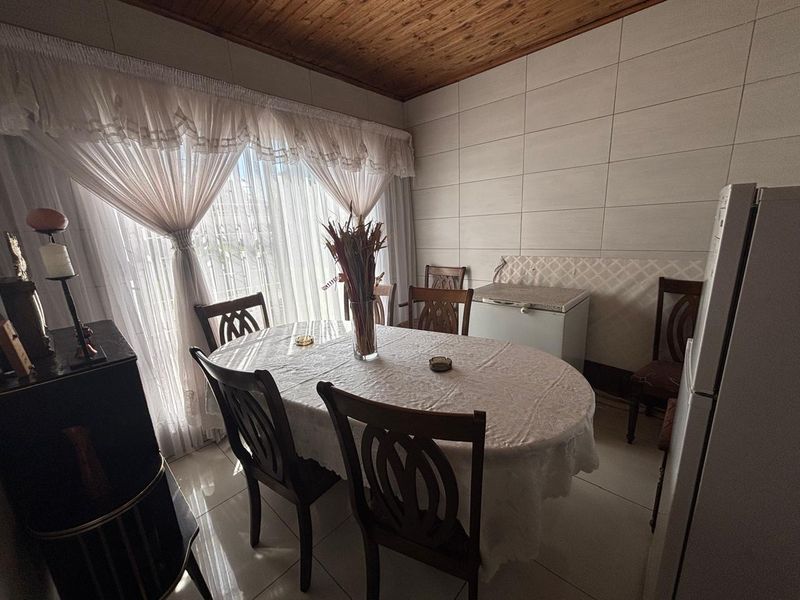 A dining area featuring tiled walls, tiled flooring, and a timber-paneled ceiling, providing a functional space for meals.