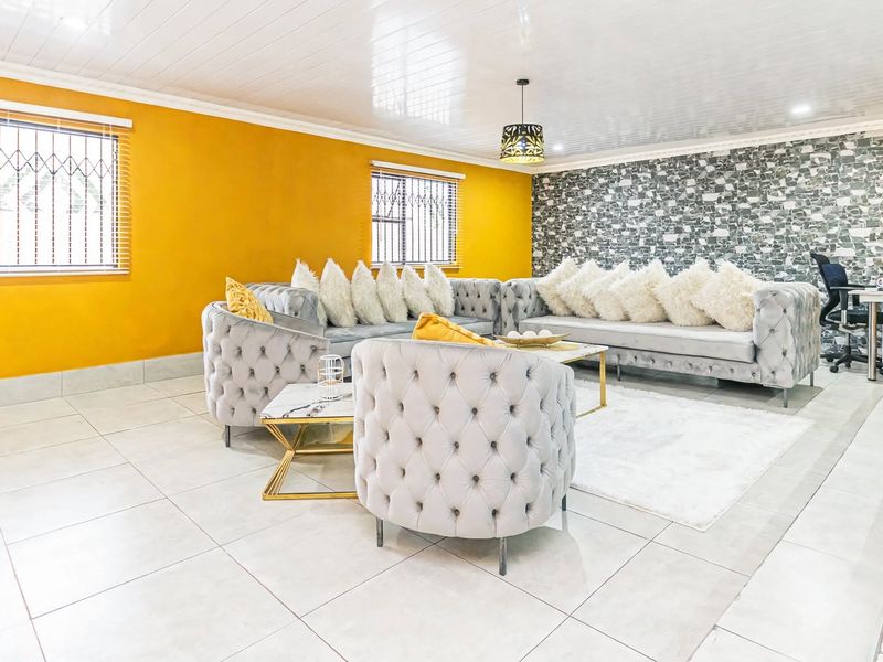 Spacious living room featuring tiled flooring, a stone-effect feature wall, and security bars on the windows.