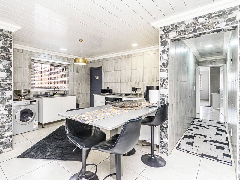 Modern kitchen featuring tiled walls, built-in cabinetry, integrated oven, hob, and a breakfast bar area with direct access to the hallway.