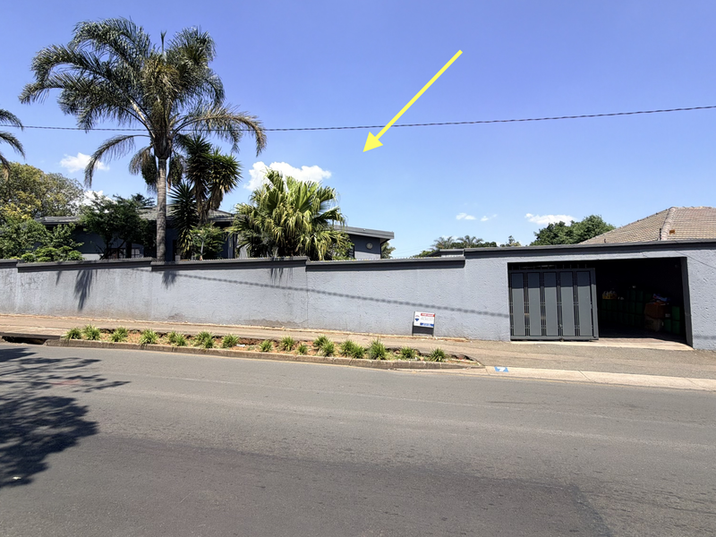 Street view of the property featuring a secure perimeter wall, sliding gate, and electric fencing, providing privacy and security for the residence.