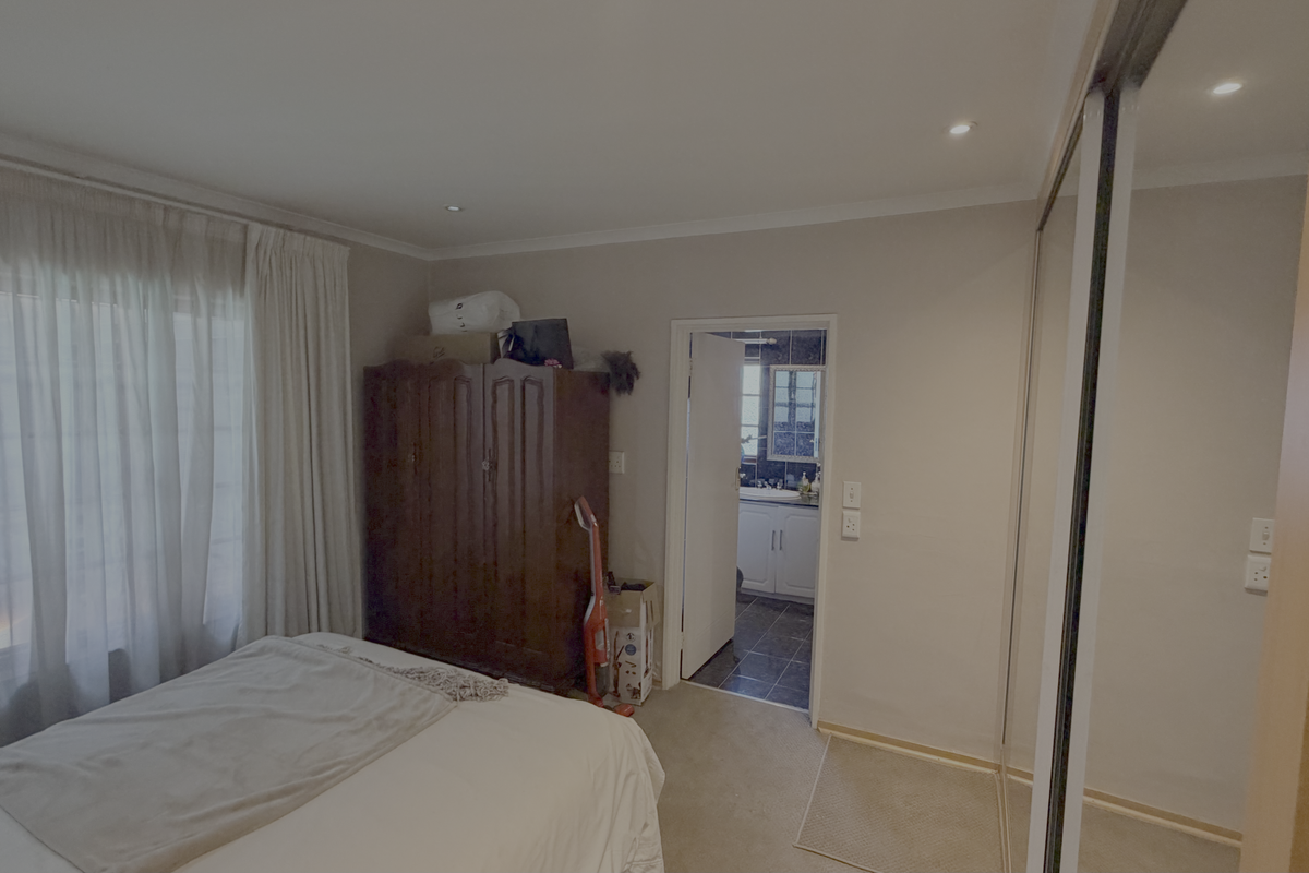 A bedroom featuring carpet flooring, recessed downlights, and a built-in sliding door wardrobe, with an adjoining bathroom visible through the doorway.