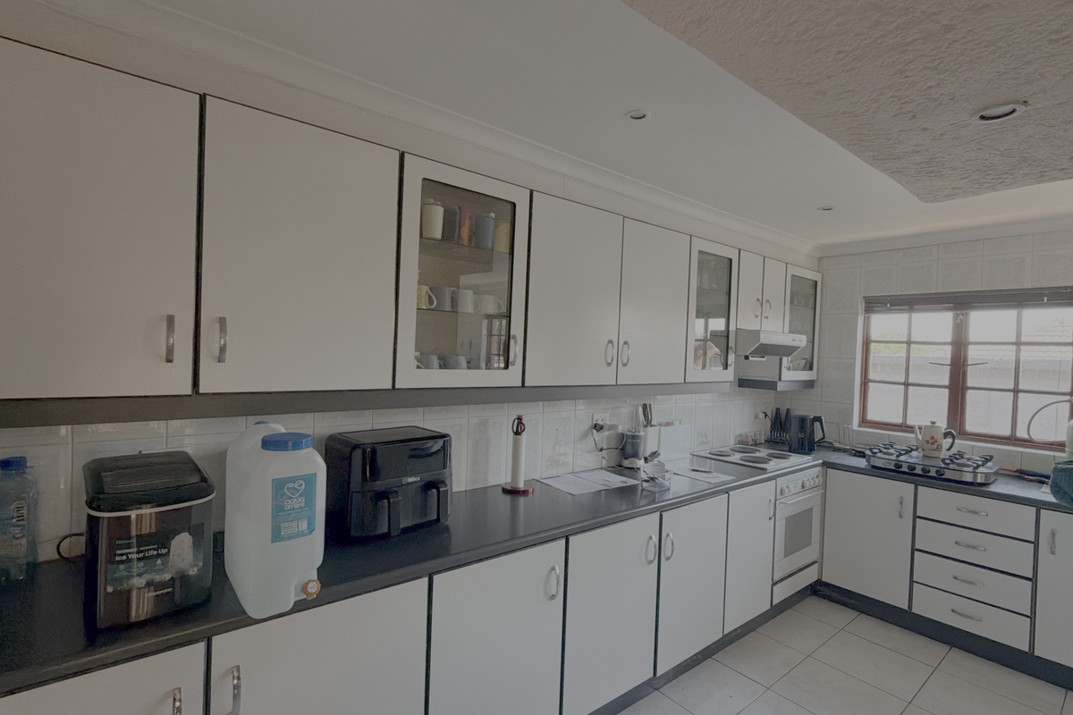 A functional kitchen featuring white cabinetry, dark laminate countertops, a built-in oven with hob, and tiled flooring, offering a clean and practical workspace.