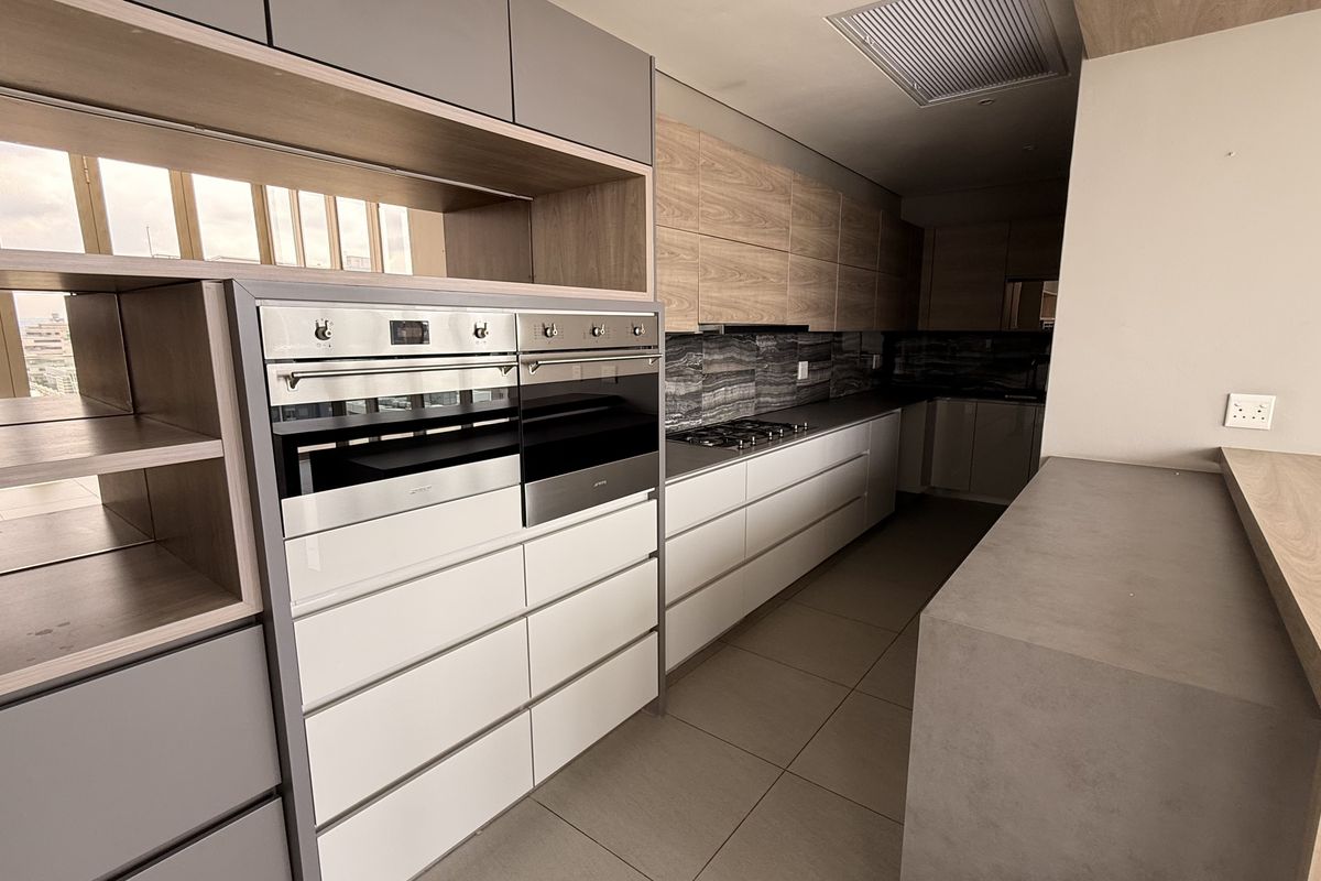 Modern penthouse kitchen featuring high-end built-in double ovens, gas hob, sleek cabinetry, and stone countertops with a clean, contemporary finish.