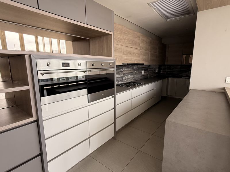 Modern penthouse kitchen featuring high-end built-in double ovens, gas hob, sleek cabinetry, and stone countertops with a clean, contemporary finish.