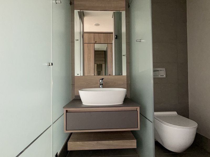 Modern bathroom featuring a wall-mounted vanity with vessel sink, wall-hung toilet, and frosted glass partitions, offering a clean and contemporary aesthetic.